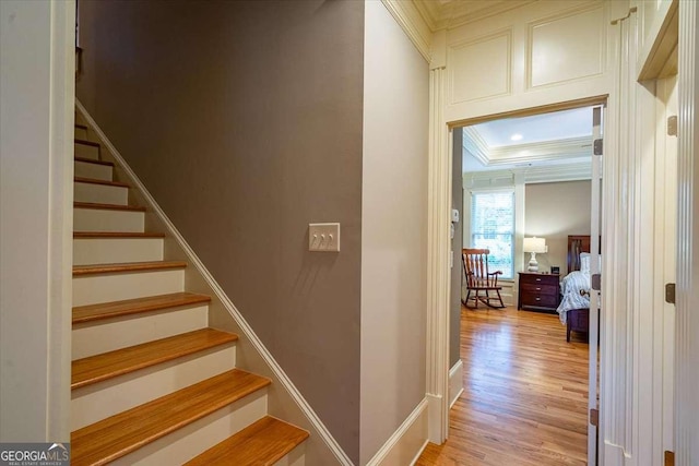 stairs featuring baseboards, ornamental molding, and wood finished floors