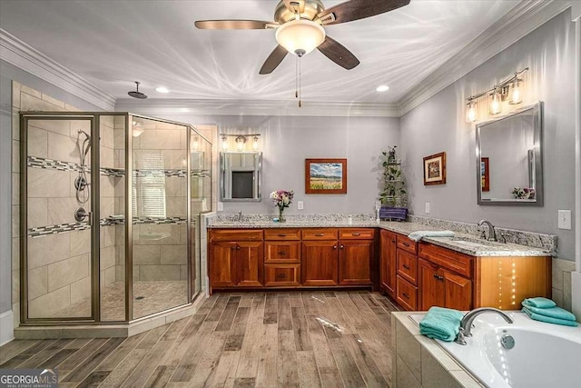 full bath featuring crown molding, a stall shower, a sink, and wood finished floors