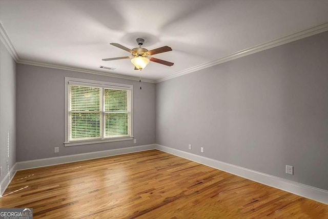 unfurnished room with baseboards, wood finished floors, visible vents, and crown molding