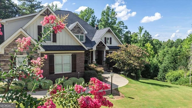 craftsman-style home featuring brick siding, board and batten siding, a shingled roof, and a front lawn