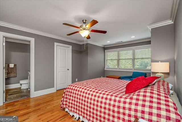 bedroom featuring ornamental molding, a ceiling fan, ensuite bath, wood finished floors, and baseboards