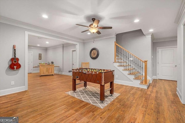 game room featuring light wood-style floors, ornamental molding, baseboards, and a ceiling fan