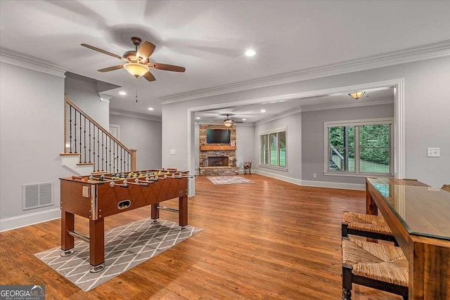 recreation room with a fireplace, wood finished floors, a ceiling fan, visible vents, and baseboards