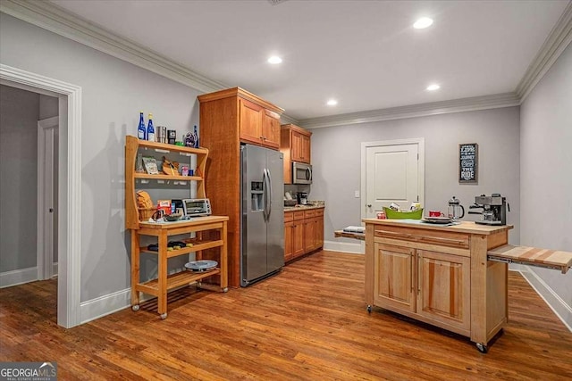 kitchen with dark wood-style floors, stainless steel appliances, light countertops, and crown molding