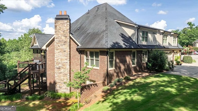 view of home's exterior featuring driveway, a garage, a chimney, a yard, and brick siding