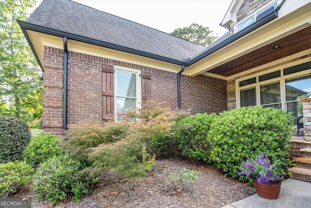 view of side of property with brick siding and a shingled roof