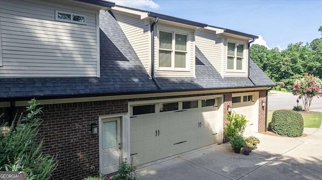 view of home's exterior featuring a garage, driveway, brick siding, and a shingled roof