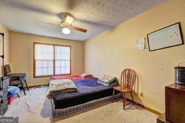 carpeted bedroom with a textured ceiling, baseboards, and a ceiling fan