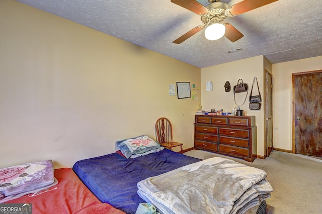 bedroom with visible vents, baseboards, a ceiling fan, a textured ceiling, and carpet floors