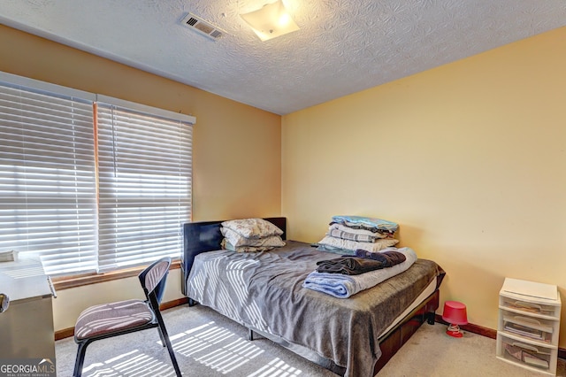 bedroom featuring carpet, visible vents, a textured ceiling, and baseboards