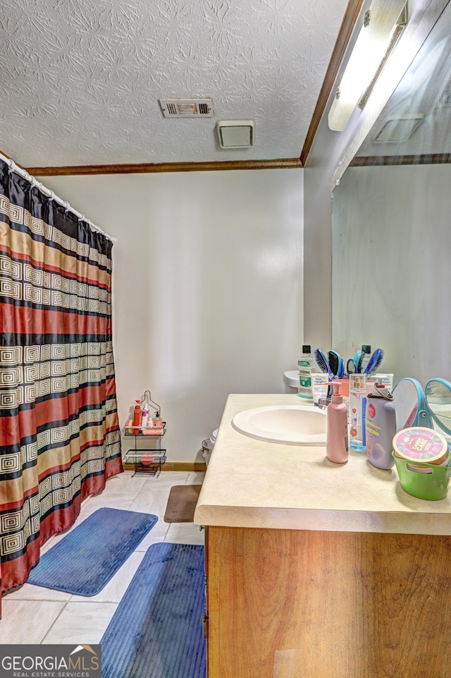 bathroom featuring a textured ceiling, visible vents, vanity, tile patterned floors, and crown molding