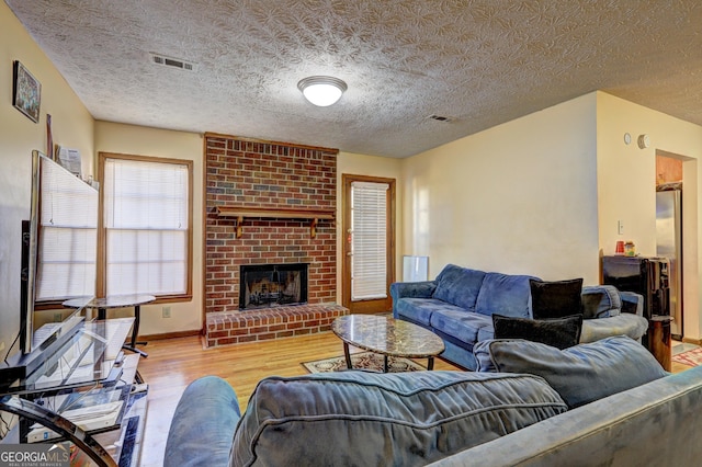 living area with a fireplace, wood finished floors, visible vents, and baseboards