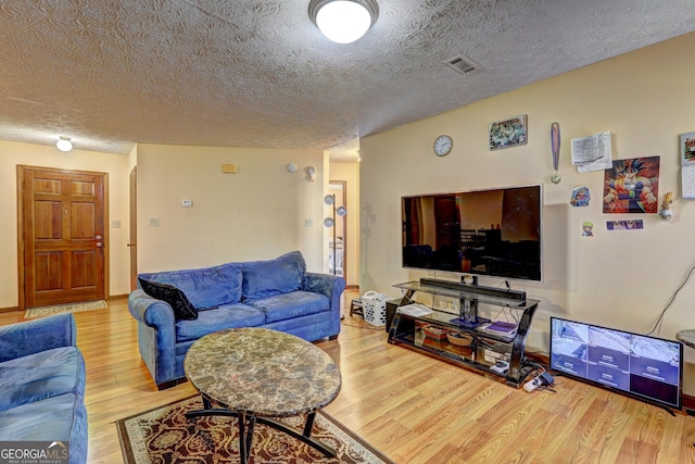 living room featuring a textured ceiling, wood finished floors, and visible vents