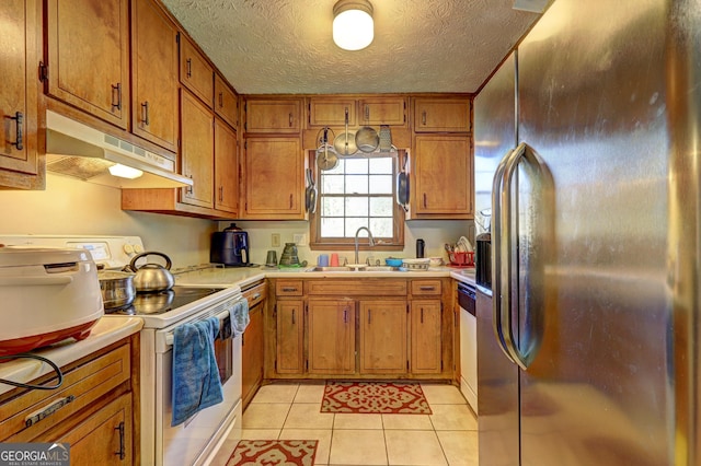 kitchen featuring brown cabinets, light countertops, a sink, white appliances, and under cabinet range hood