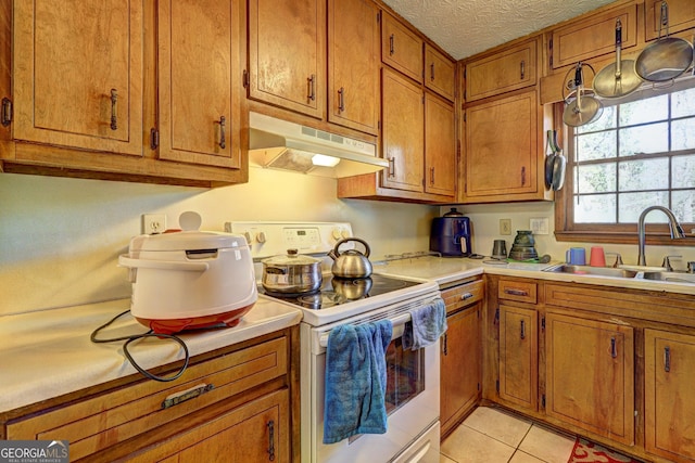 kitchen with electric stove, brown cabinets, and under cabinet range hood