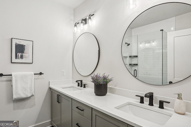 bathroom featuring double vanity, a stall shower, a sink, and baseboards