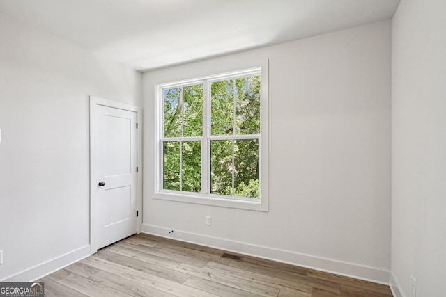 unfurnished room featuring light wood-style floors, visible vents, and baseboards