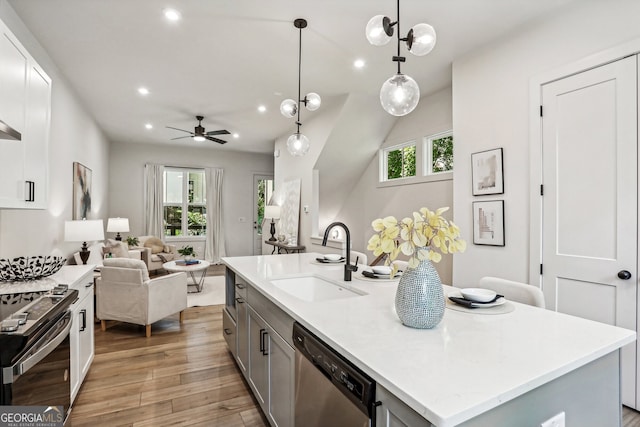 kitchen with light wood finished floors, light countertops, stainless steel dishwasher, a sink, and range with electric cooktop