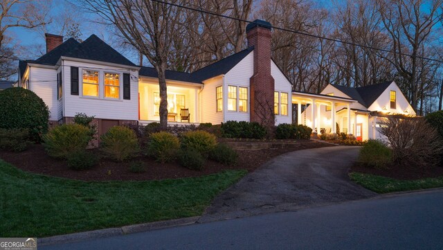 view of front of house featuring a shingled roof, a front yard, and a chimney