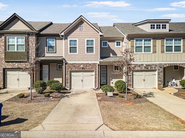 townhome / multi-family property featuring driveway, stone siding, and a garage