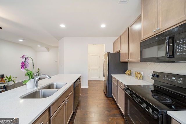 kitchen with tasteful backsplash, light countertops, dark wood-type flooring, a sink, and black appliances