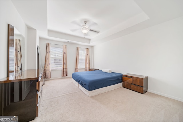 bedroom with a tray ceiling, carpet, a ceiling fan, and baseboards