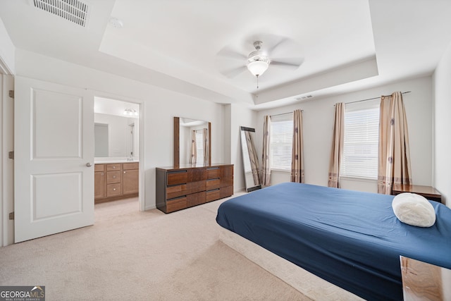 bedroom featuring light colored carpet, a tray ceiling, and visible vents