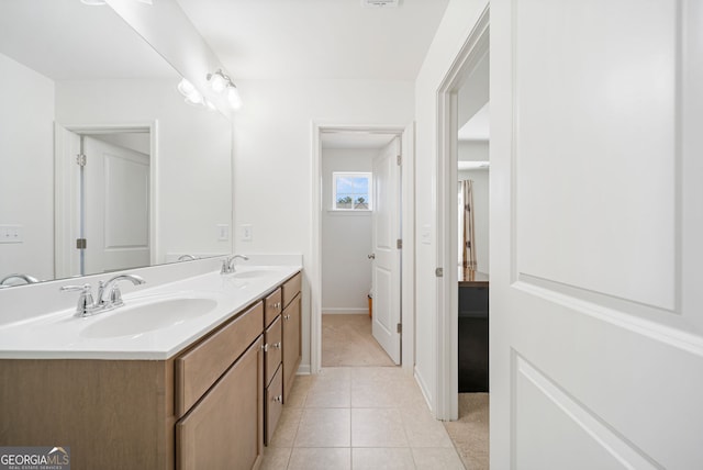 bathroom with baseboards, double vanity, a sink, and tile patterned floors