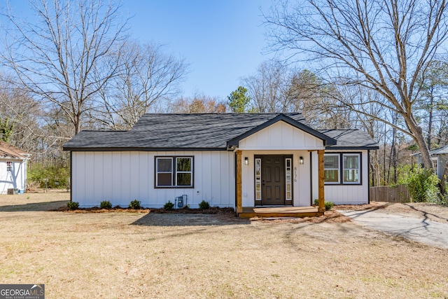 view of front of home featuring a front lawn, board and batten siding, a shingled roof, and fence