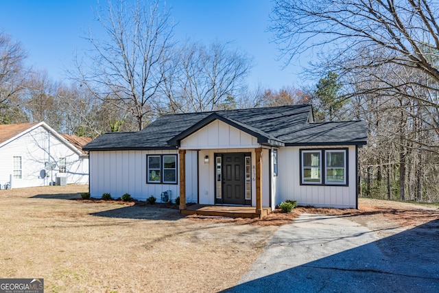 view of front of property with a shingled roof, board and batten siding, and a front yard