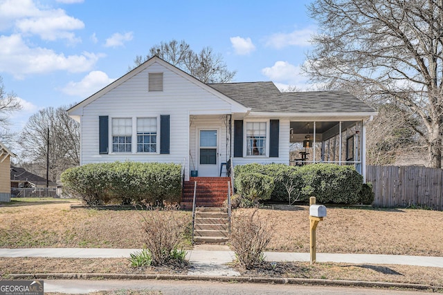 bungalow-style house with a shingled roof and fence