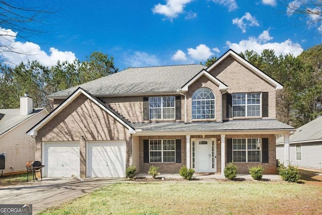 view of front of home featuring a garage, aphalt driveway, a front yard, and brick siding