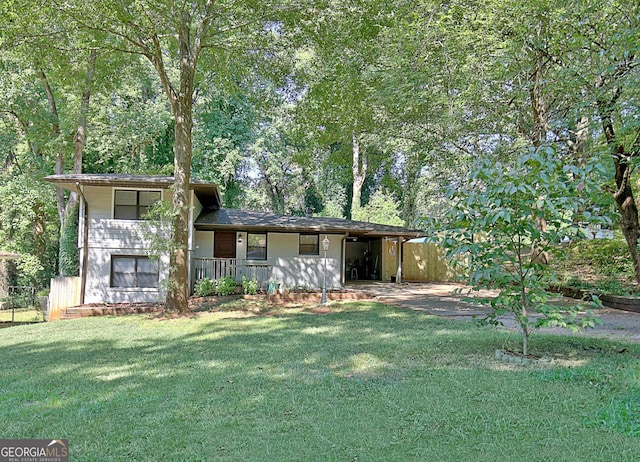 tri-level home with concrete driveway, an attached carport, a front yard, and fence