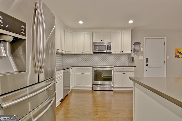 1453 Midview Dr, Decatur, GA 30032 - kitchen featuring appliances with stainless steel finishes, light wood-type flooring, decorative backsplash, and white cabinets