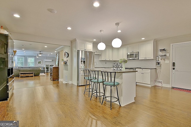 1453 Midview Dr, Decatur, GA 30032 - kitchen featuring a breakfast bar, wood finished floors, white cabinetry, appliances with stainless steel finishes, and dark countertops