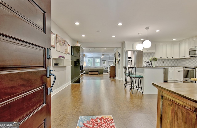 1453 Midview Dr, Decatur, GA 30032 - kitchen featuring stainless steel appliances, white cabinetry, light wood-style flooring, and backsplash