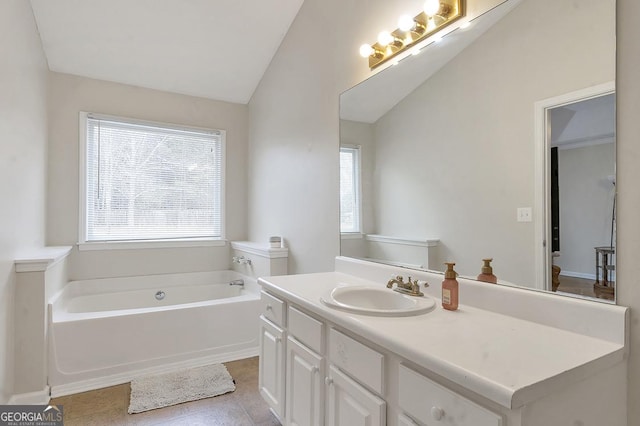 bathroom featuring lofted ceiling, a garden tub, vanity, and tile patterned floors