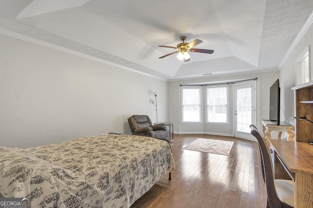 bedroom featuring baseboards, access to outside, wood-type flooring, a raised ceiling, and crown molding