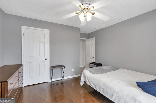 bedroom featuring dark wood-style floors, a textured ceiling, a ceiling fan, and baseboards