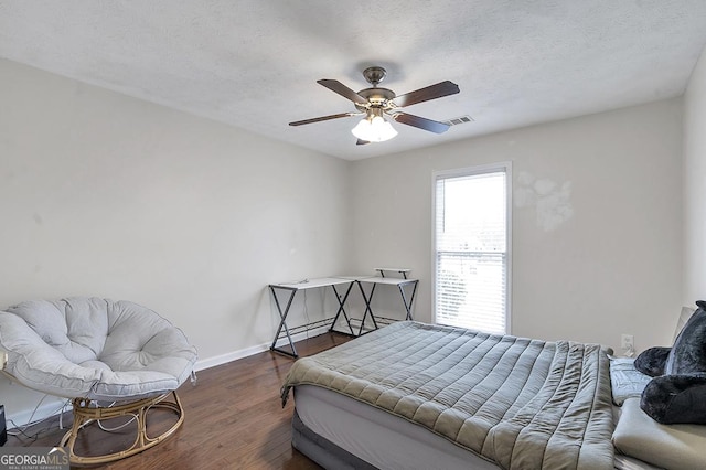 bedroom with a textured ceiling, wood finished floors, visible vents, and baseboards