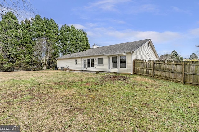 back of house featuring a chimney, fence, and a yard