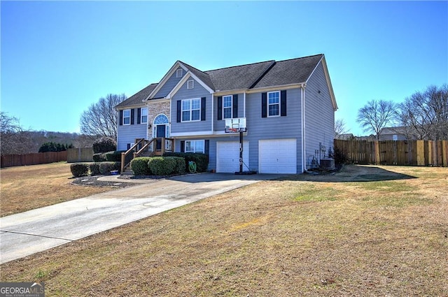 split foyer home featuring a garage, central AC, fence, driveway, and a front yard