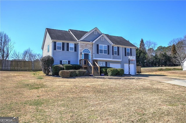 bi-level home featuring a garage, fence, a front lawn, and concrete driveway