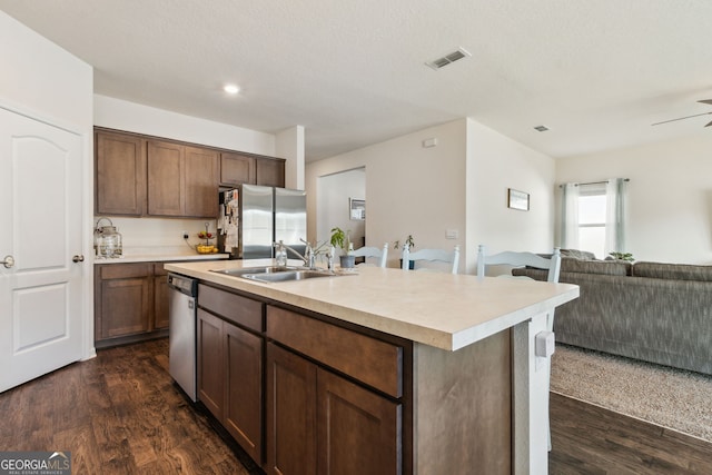 kitchen with visible vents, open floor plan, dark wood-style flooring, stainless steel appliances, and a sink