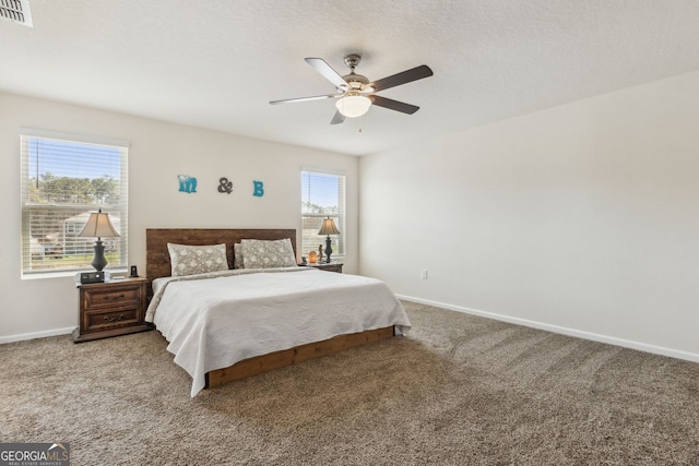 bedroom with a textured ceiling, carpet floors, visible vents, and baseboards