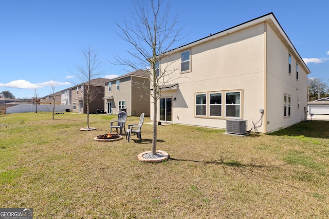 rear view of property with an outdoor fire pit, stucco siding, a yard, and central AC unit