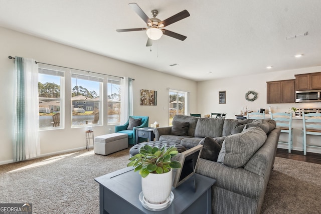 living room with baseboards, visible vents, dark colored carpet, and a ceiling fan