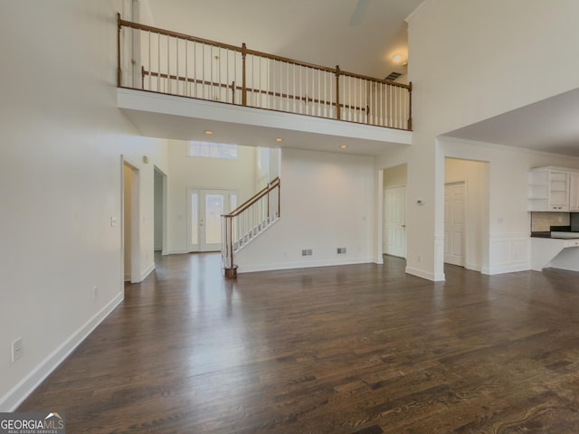 unfurnished living room with dark wood-type flooring, stairway, and baseboards