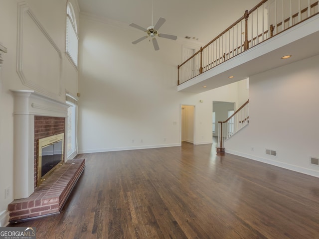 unfurnished living room featuring a brick fireplace, baseboards, visible vents, and wood finished floors