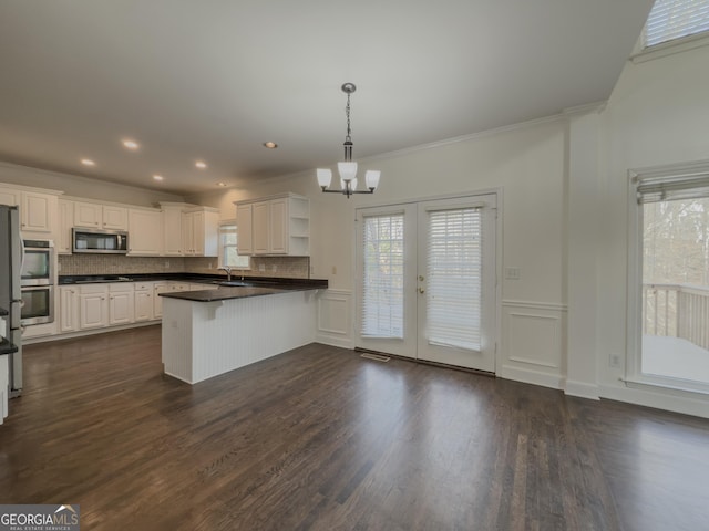 kitchen featuring a peninsula, open shelves, tasteful backsplash, stainless steel microwave, and dark countertops